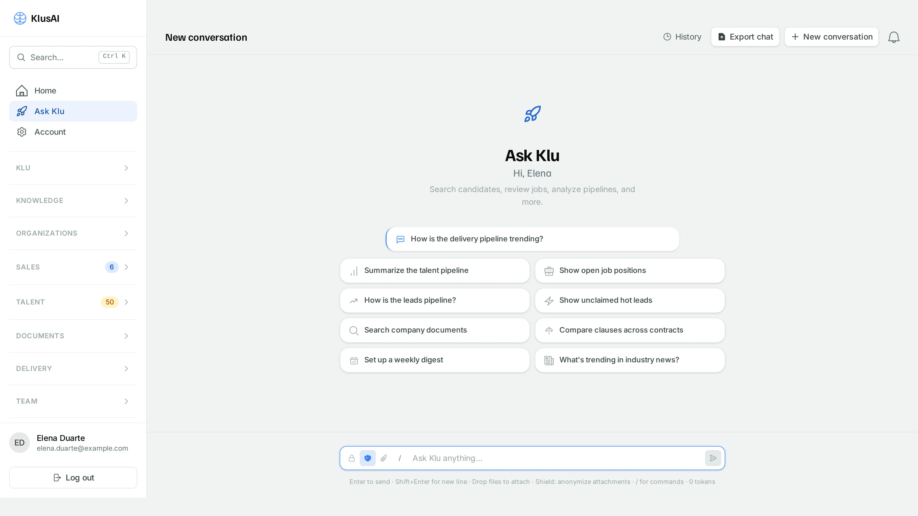 A new Klu conversation: suggested questions as clickable cards above a composer, with a shield toggle, an attachment button and a slash-command hint.